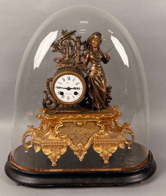 une horloge en or sous un dôme de verre sur une table