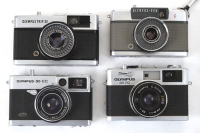 four cameras are lined up in a row on a white surface