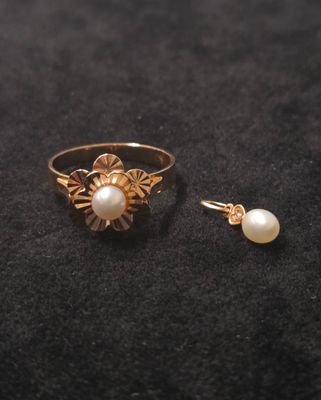 un gros plan d'une bague et d'une boucle d'oreille en perle posées sur une surface noire