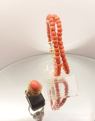 an orange bead necklace and a ring on a table