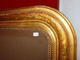 a mirror with a gold frame on a red wall