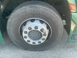 a green bus with a flat tire parked in a parking lot