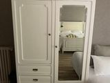 une photo d'une chambre à coucher avec un lit et une armoire blanche