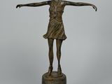 statue en bronze représentant une femme debout sur un socle, les bras tendus