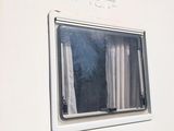 a white trailer with a window and curtains on it