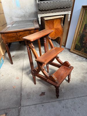 un tabouret en bois posé devant un tableau