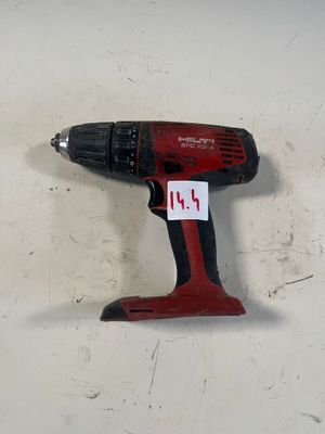 une perceuse sans fil rouge posée sur une surface blanche