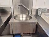 a sink in the middle of a kitchen with a blue trash can underneath it