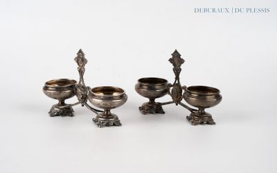 trois bougeoirs plaqués argent posés sur des socles, disposés sur une surface blanche