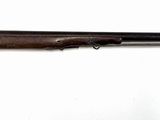 Le fusil est posé sur la table, à côté de la chaise rouge.