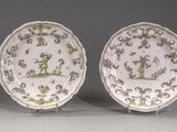 une paire d'assiettes vertes et blanches ornées de personnages et de fleurs