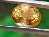 a close up of a yellow diamond being held by a pair of pliers