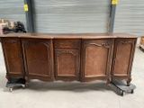 un grand buffet en bois monté sur roulettes, dans un entrepôt