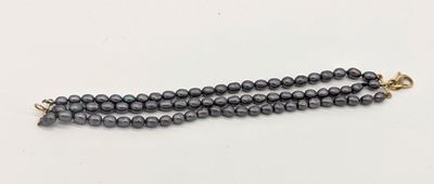 un gros plan d'un collier de perles noires posé sur une surface blanche