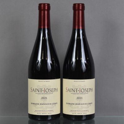 two bottles of wine sit on a glass table in front of a gray wall