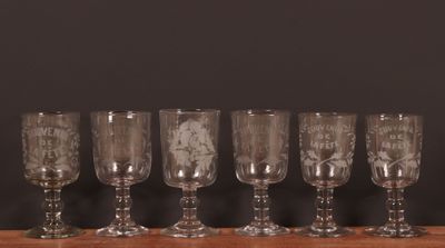 Six verres à vin sont alignés sur une table en bois