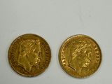 two pieces of gold coins sitting on top of a white surface
