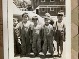 a black and white photo of a group of boys in overalls