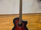 une guitare acoustique posée sur un parquet devant un mur