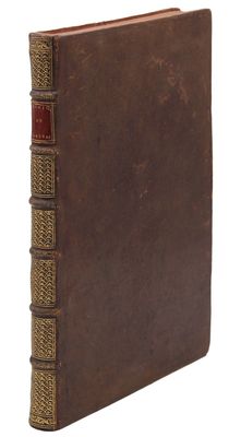 un vieux livre à la couverture brune posé sur une surface blanche