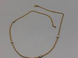 un bracelet en chaîne d'or orné de perles sur fond blanc