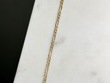 a close up of a gold chain bracelet on a marble surface