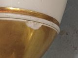 a white vase with a gold rim sitting on a table