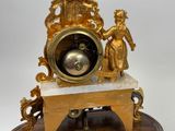 a gold clock sitting on top of a wooden stand