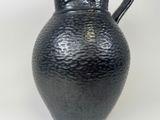 a black vase with a black handle on a white surface