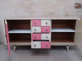 a pink and white cabinet with drawers and shelves