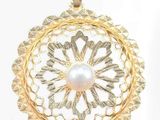 a close up of a gold pendant with a pearl in the center