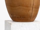 a wooden vase sitting on top of a white pedestal