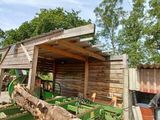 a tractor parked in front of a shed with a pile of wood