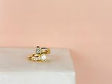 un gros plan d'une bague en or sertie de deux diamants posée sur un socle