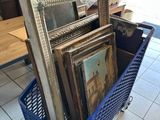 a blue basket filled with framed pictures on the floor