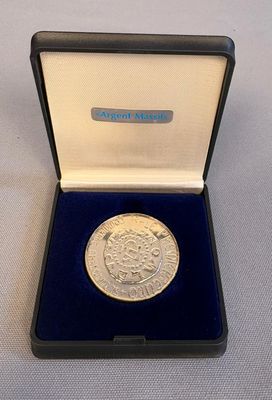 l'image d'une pièce d'argent dans une boîte noire posée sur une surface blanche