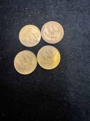 four different types of gold coins on a black surface