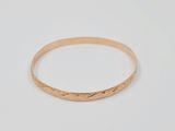 a close up of a gold bang bracelet on a white background