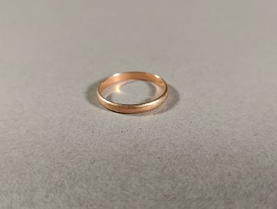 une bague en or posée sur une surface blanche