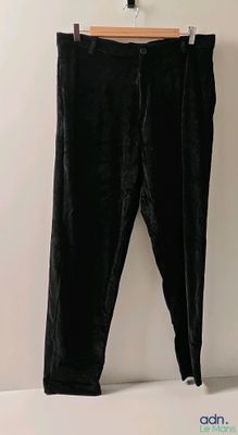 un pantalon en velours noir suspendu à un cintre devant un mur blanc