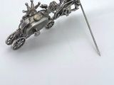 an antique silver broochle with a horse drawn carriage on it
