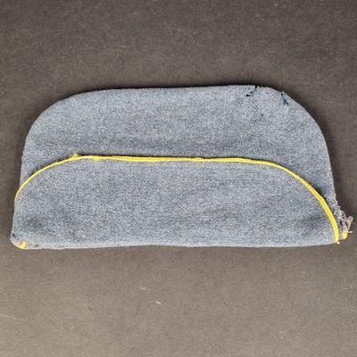 un petit sac gris avec une fermeture éclair jaune posé sur une table