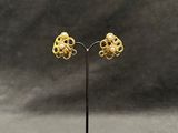 a pair of gold earrings on a black stand