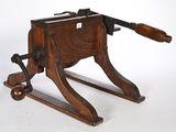 une vieille machine en bois munie d'une poignée en bois, sur fond blanc