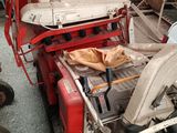 a red and white tractor parked next to a pile of junk