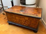 a wooden chest sitting on a hard wood floor next to a heater