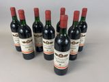 six bottles of red wine lined up in a row on a table