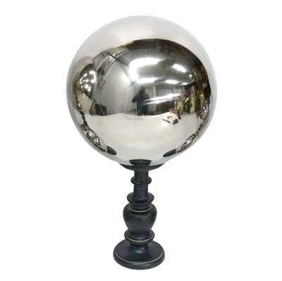 une boule argentée posée sur un socle noir, sur fond blanc