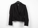 un blazer noir suspendu à un cintre devant un mur blanc