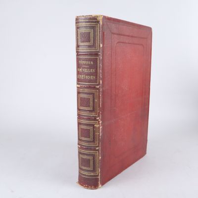 un vieux livre à la couverture rouge posé sur une surface blanche
